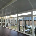 Inside a glass enclosure with white-framed windows and a dark wood floor