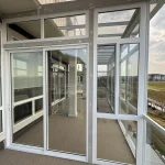 Glass enclosure with white-framed sliding doors and a clear roof