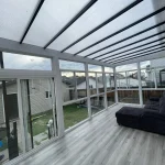 Inside a glass enclosure with a grey floor, clear roof and sofa