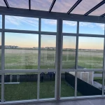 View through large white-framed windows of a glass enclosure at sunset