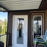 Brown-framed enclosure with a white glass door and patio chairs