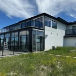 Black-framed glass enclosure at the back of a modern home with a ladder beside it