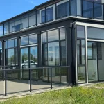 Black-framed glass enclosure with a glass railing and lawn in front