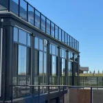 Tall black-framed glass enclosure with a glass railing on a modern home
